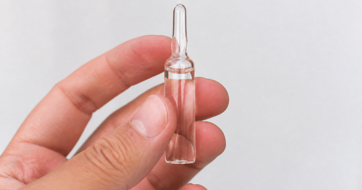 Main tenant ampoule remplie de liquide transparent sur fond blanc