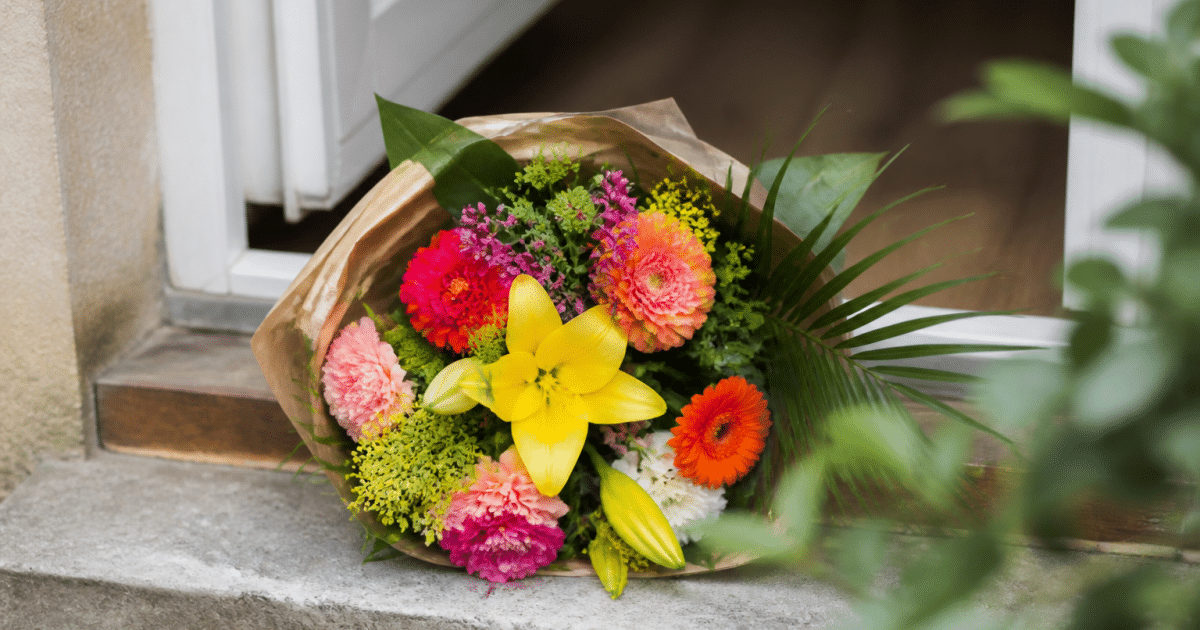 Bouquet de fleurs colorées remis à domicile sur seuil