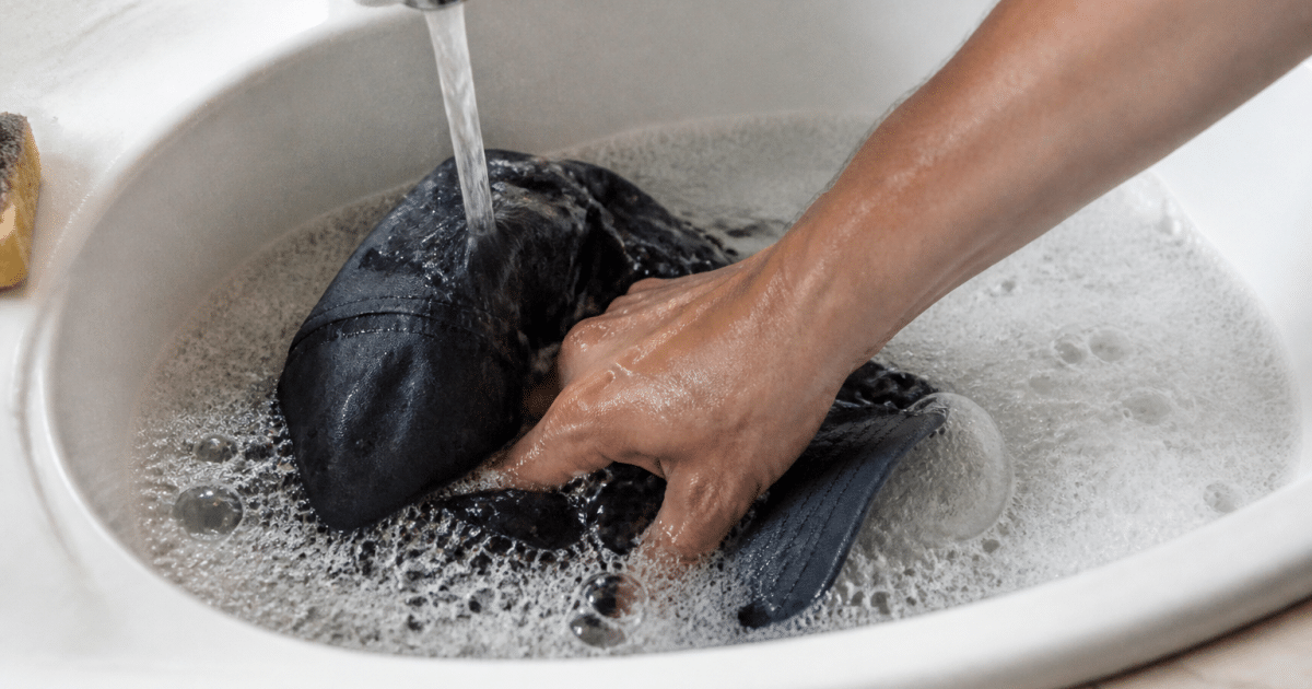 Main immergee dans eau savonneuse nettoyant casquette sous robinet