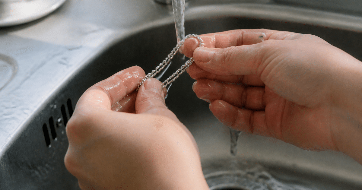 Mains tenant un bracelet argent sous l'eau courante