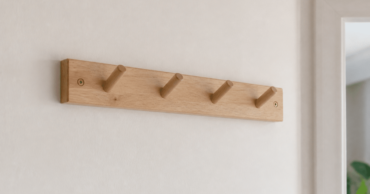 Patere murale en bois clair fixee au mur blanc