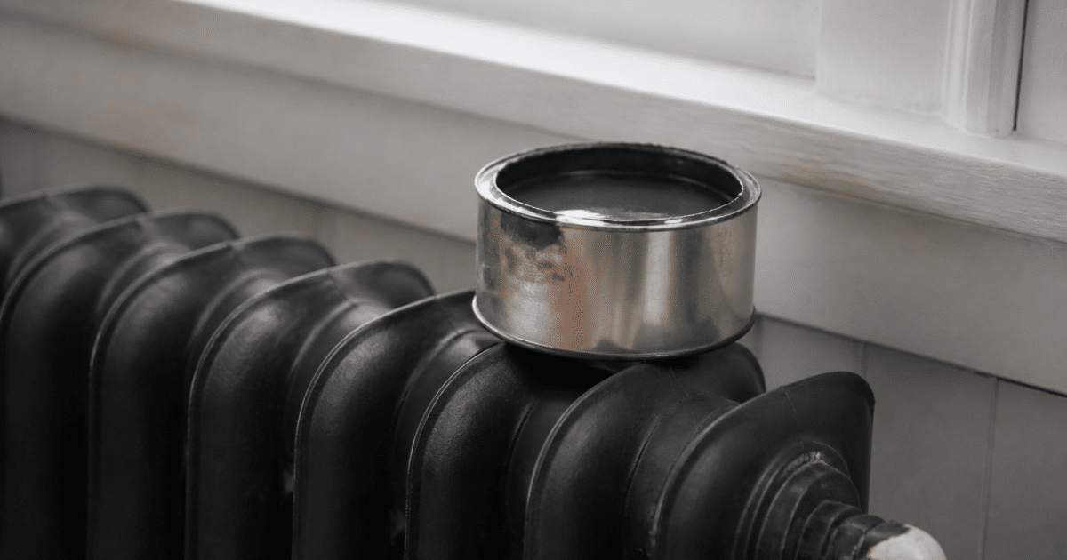 Pot ouvert de peinture metallique reposant sur radiateur fonte noir