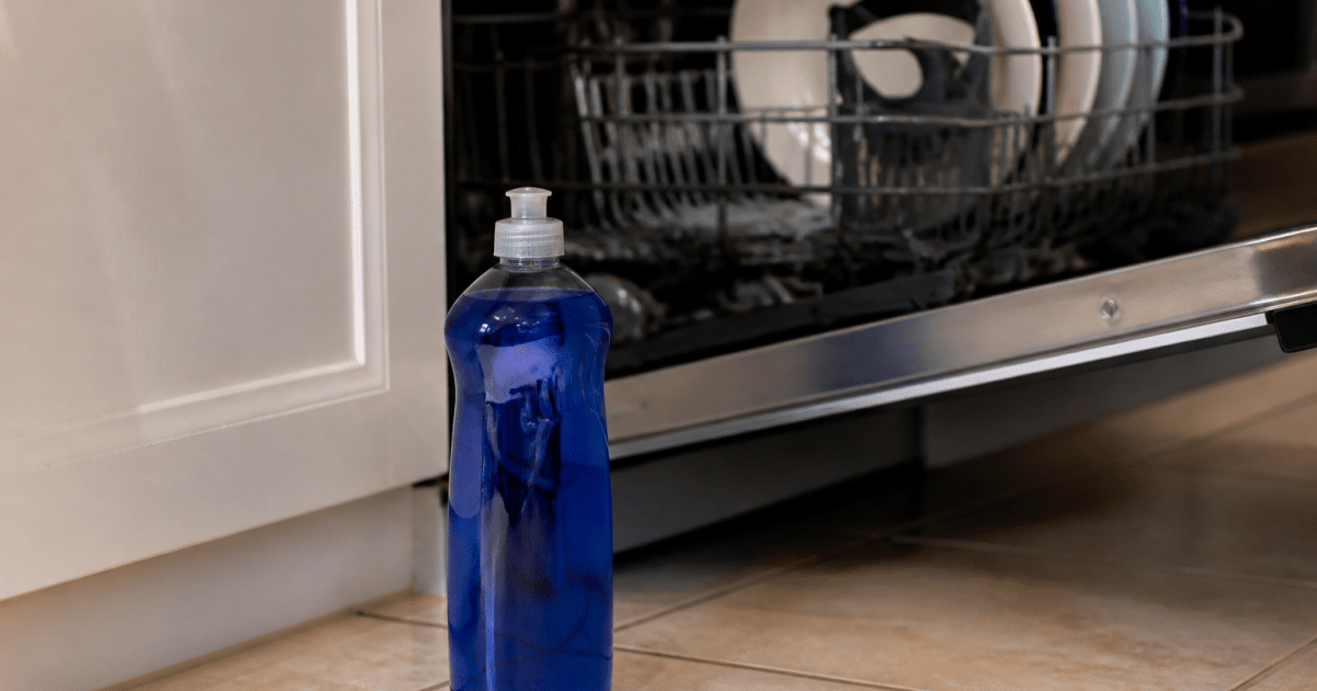 Bouteille bleue de produit de rinçage posée devant lave-vaisselle ouvert