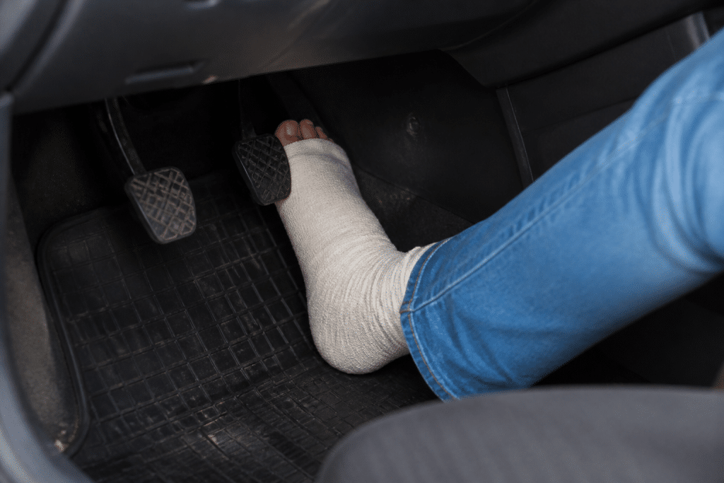 Personne appuyant sur pédale frein voiture avec pied bandé